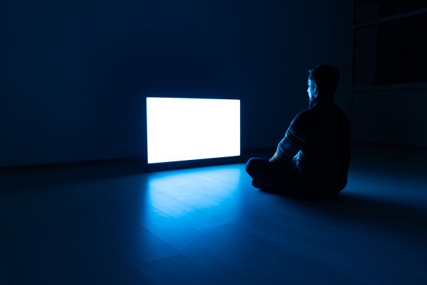 在黑暗的房间里，坐在电视机前地板上的那个人图片下载