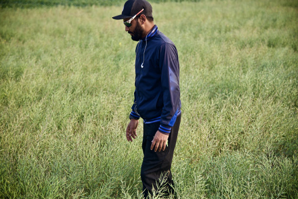 一个年轻人站在绿色芥菜田里图片下载