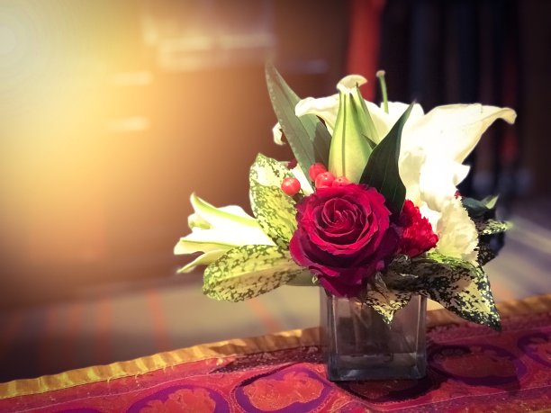 红色的桌子上，玻璃上的红玫瑰，带有黄色的光效果图片下载