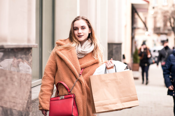 美丽的年轻金发在户外抱着包裹购物后图片下载