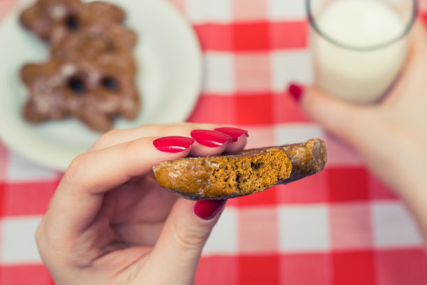 近距离的照片biiten饼干在女人的手和牛奶的背景图片下载