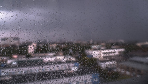 窗外俯瞰春夏多雨的城市。玻璃上有细小的水滴。股票的背景,照片图片下载