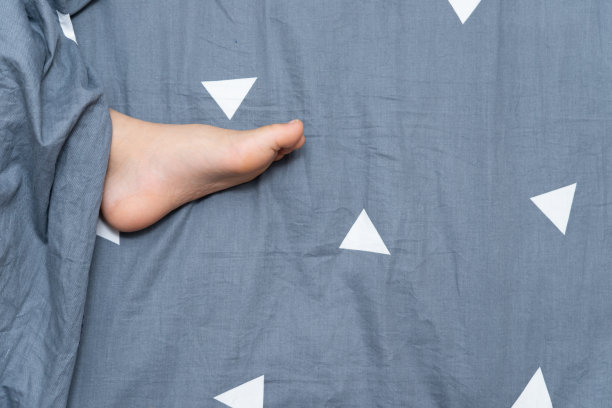 孩子睡在床上，腿从被单里伸出来图片下载