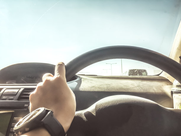 在炎热的天气里驾驶的概念从车的内部视图，而司机的手在方向盘上和其他汽车是运动模糊，抽象模糊图片下载
