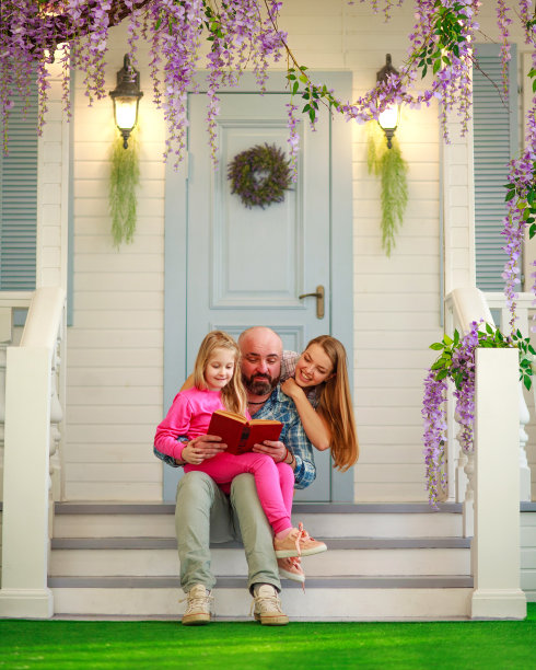 父母父母和他们的女儿在院子里读一本书的传统春天的家图片下载