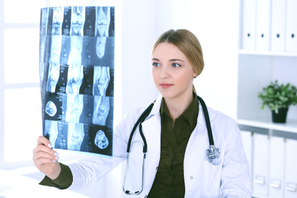一位女医生在医院窗户附近检查x光照片。在工作中的外科医生或整形外科医生医疗保健理念。理疗师穿的卡其色衬衫很好看图片下载