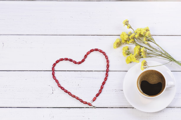 一杯新鲜的咖啡，一束野生的黄花，一条珊瑚心形的项链，白色的木质背景和复制空间的情人节。俯视图，平放。图片下载