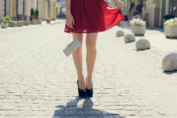 苗条的女士穿着时髦的衣服过生日。她穿着优雅美丽的裙子，黑色高跟鞋，拿着一个包。近距离，裁剪照片图片下载