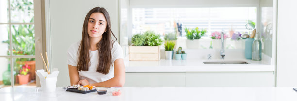 广角图片美丽的年轻女子吃亚洲寿司从交付轻松与严肃的表情在脸上。简单自然的看相机。图片下载