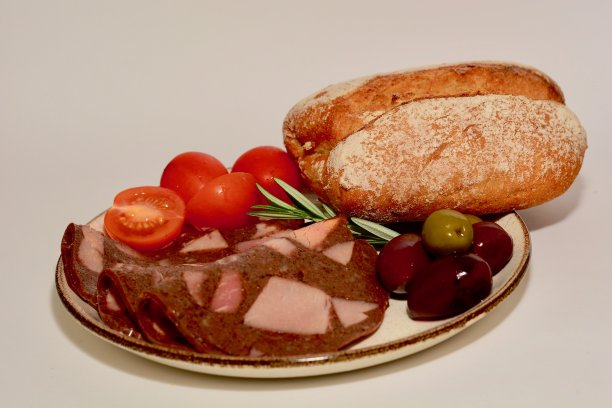 一顿丰盛的食物或零食的特写照片，包括一些肉片，西红柿，橄榄和黑麦面包面包。图片下载