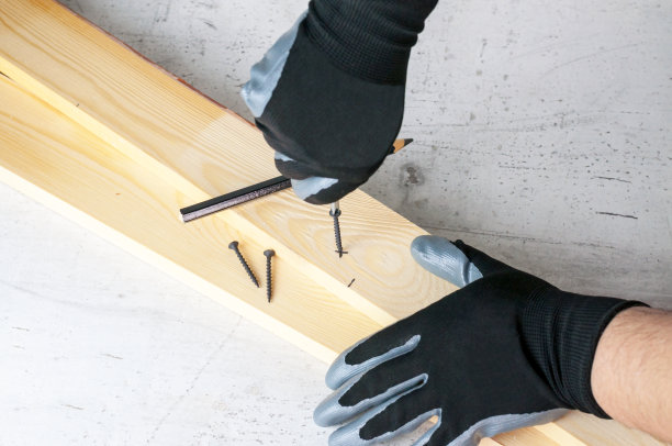 一名男子在木条上做标记，以便进一步拧紧螺钉。Diy家居概念图片下载