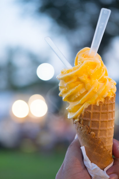 手里拿着橙色的蛋卷冰淇淋。由百香果制成的橙子冰淇淋图片下载