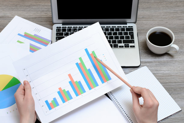 工人看图形。俯视图手握图形，笔记本电脑，一杯咖啡图片下载