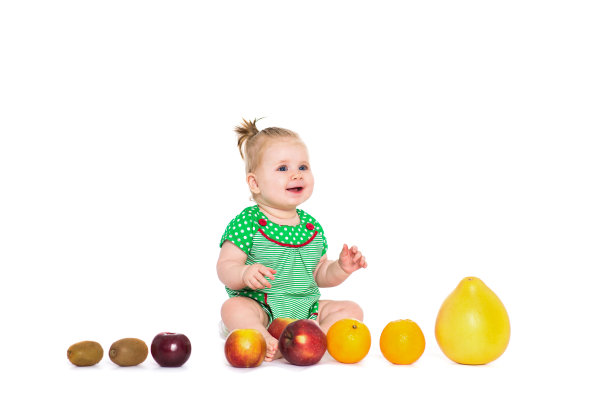 女婴坐在水果和蔬菜，孤立的白色图片下载