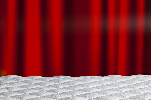 桌上是白色绗缝皮革，背景是红色窗帘图片下载