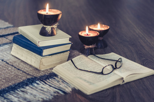 燃烧的水疗香薰蜡烛椰子壳，格子，眼镜和书，舒适的家庭室内背景图片下载