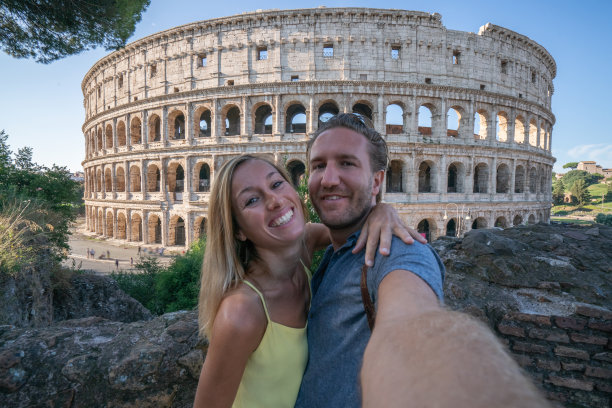 一对年轻夫妇在罗马享受意大利旅行，在著名的罗马斗牛场前拍照图片下载