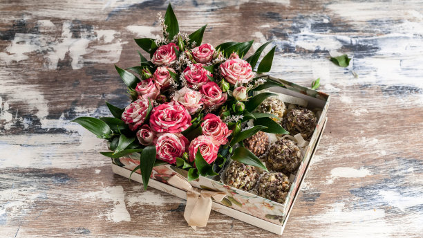 木桌上有玫瑰和巧克力的礼盒。图片下载