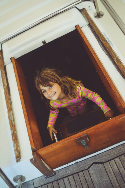 一个孩子在帆船上，爬上船舱，很开心图片下载