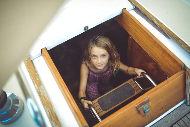 一个孩子在帆船上，爬上船舱，很开心图片下载