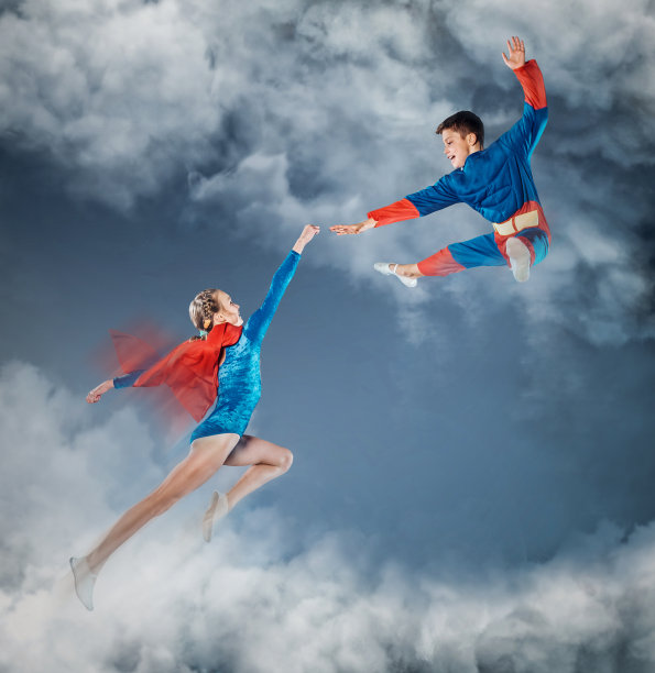 穿着超人衣服的有趣孩子在天空中飞翔。图片下载