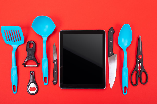 俯视图的平板和厨房用具旁边孤立在一个红色的背景图片下载
