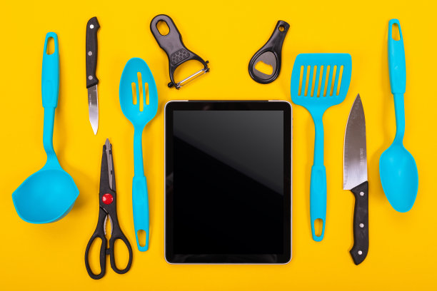 俯视图的平板和厨房用具旁边孤立在一个黄色的背景图片下载
