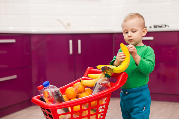 快乐的小男孩推着购物车。小男孩吃香蕉。购物、打折、销售理念图片下载