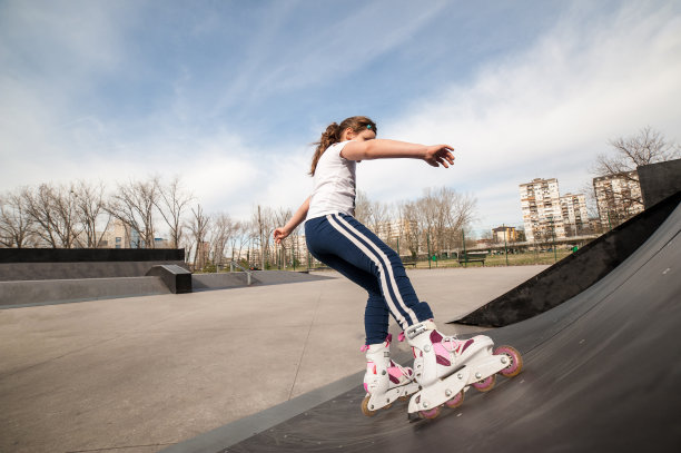 小女孩在滑板公园的坡道上滑旱冰鞋图片下载