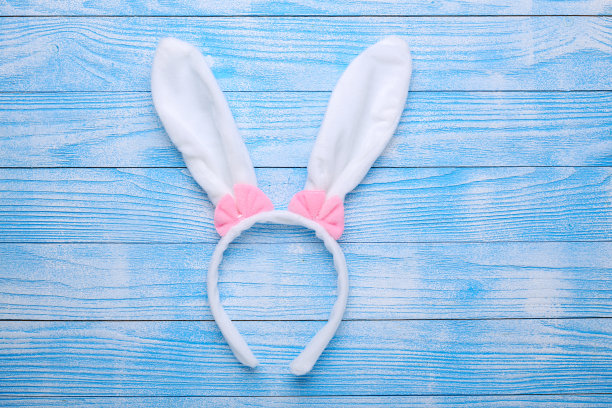 蓝色木制背景上的白兔耳朵。象征复活节快乐平躺图片下载