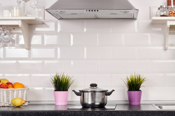 在公寓的一个照明厨房的内部。明亮的家居室内装饰项目，水果，花在一盆，钢罩。明亮的现成图片为您的个人设计图片下载