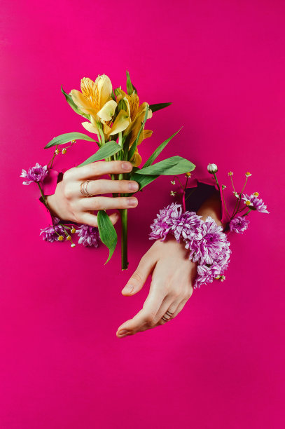 女人的手通过破纸的特写拿着黄色的紫花和菊花手镯图片下载