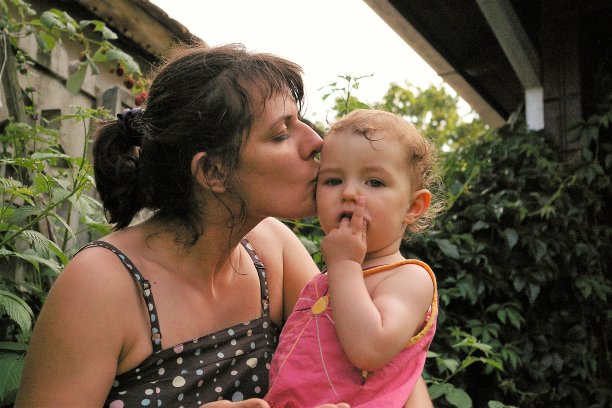 年轻的母亲亲吻女儿的脸颊图片下载