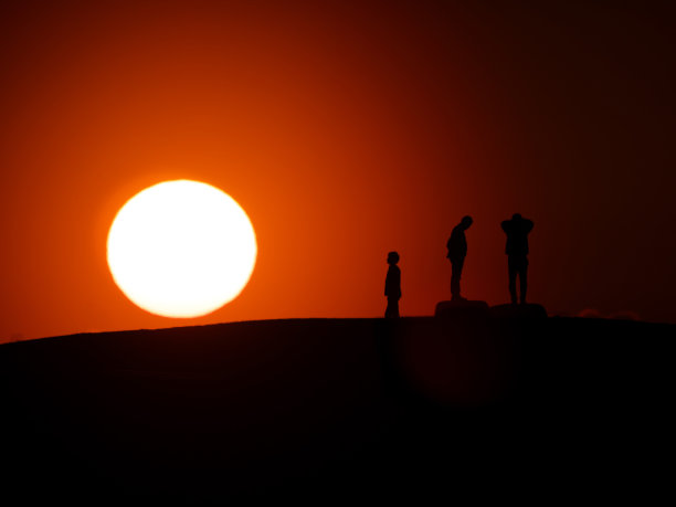 日落时山上三个人的剪影图片下载