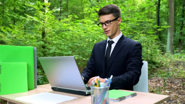 商人在森林里用笔记本电脑工作，受到自然美景和生态的启发图片下载