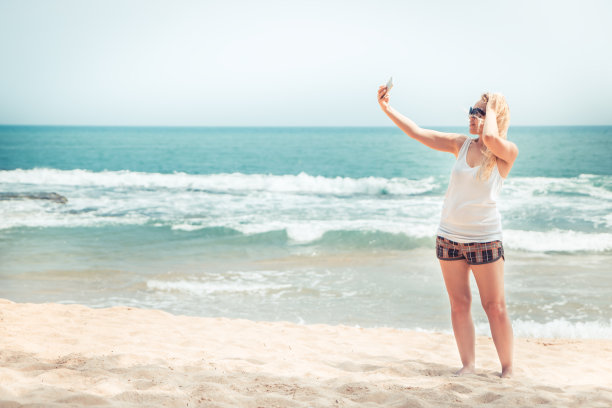 美丽孤独的女人旅行者在海滩上拍照自拍在海滩旅行假期度假社交媒体概念旅行生活复古风格图片下载