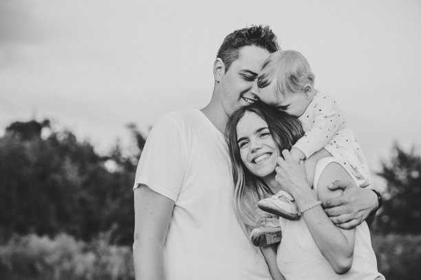 一个快乐的年轻家庭花时间在一起的自然，度假，户外。妈妈抱着女儿站在草地上。家庭度假的概念。黑白照片。图片下载