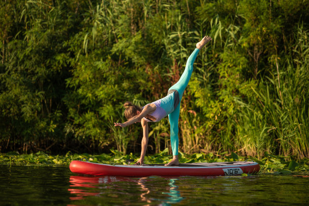 年轻女子做手倒立立桨板的照片。她穿着紧身裤和上衣。图片下载