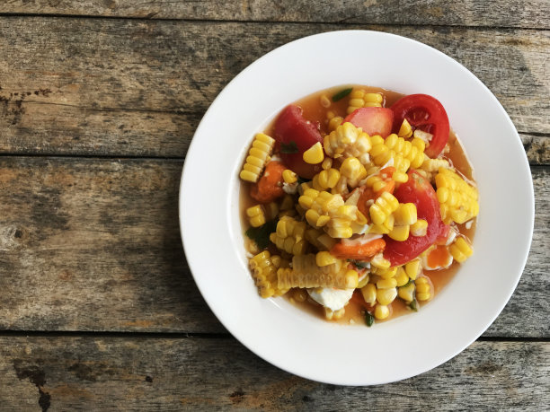 木桌上的白碟里有玉米辣味沙拉和鸡蛋。泰国传统和流行的食物，健康的菜单，美味的泰国食物图片下载