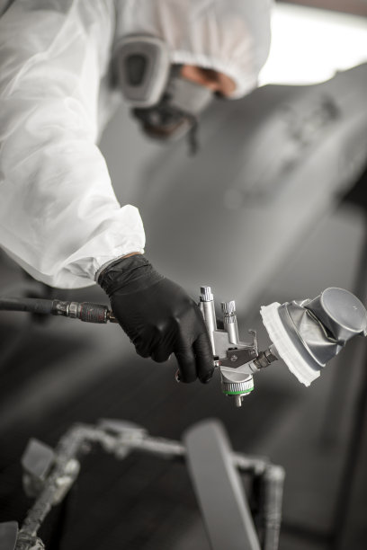 汽车油漆工在喷漆室用喷漆枪喷涂汽车零件图片下载