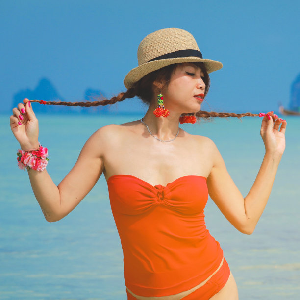 年轻女子在阳光下身穿红色比基尼，绿松石色的深海为背景。热带岛屿天堂假日旅游图片下载