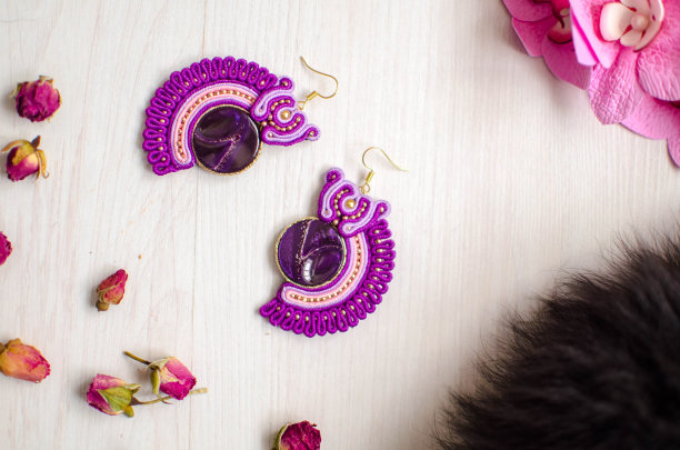 串珠手镯和耳环套装。粉色和紫色的沙发珠宝与花在白色的木制背景。女性的配件图片下载