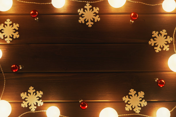 帧节日卡片。沿着框架的周长有明亮的花环。圣诞节的木制装饰用雪花，红色的玻璃球在棕色的古色古香的老木板的背景。圣诞假期图片下载