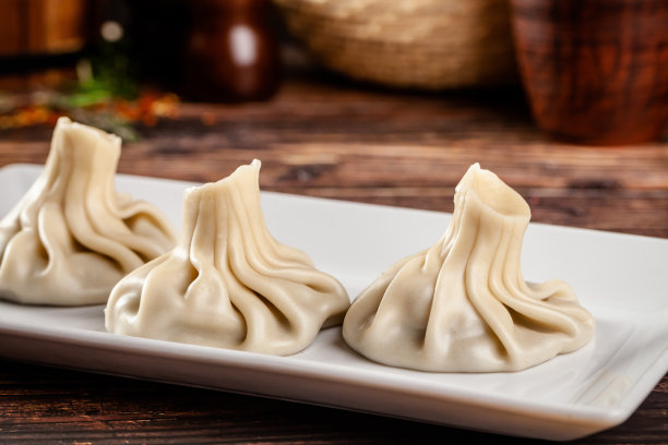 格鲁吉亚菜的概念。Khinkali白面团和肉。在格鲁吉亚餐厅里，在木桌上用白色盘子端菜。的背景图片。本空间图片下载