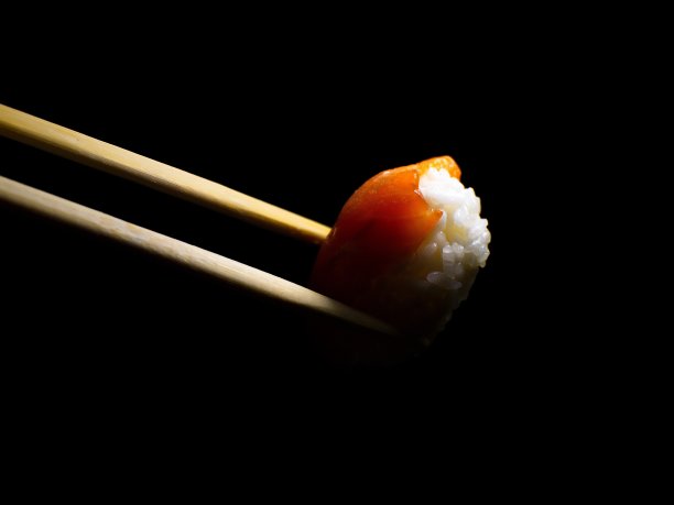 日本的食物。极简主义。食物的照片。用木筷子夹寿司。图片下载