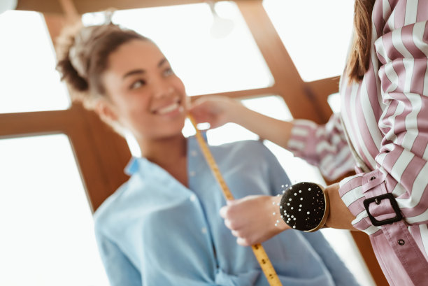 裁剪照片的年轻时装设计师为非洲模特测量图片下载