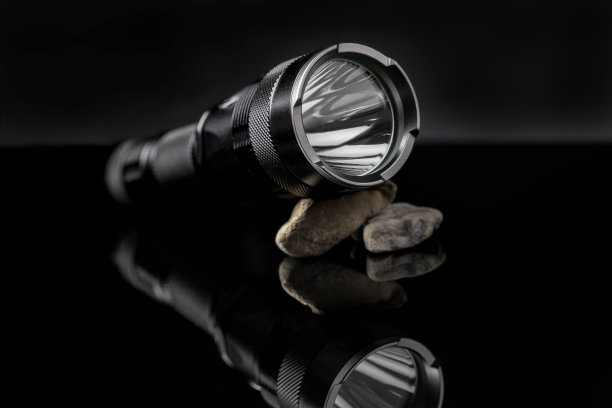 黑色手电筒照在石头上，映照在黑色背景上。图片下载