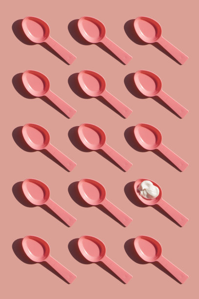 粉红色的塑料勺子排成一排，在粉红色的背景上。图片下载