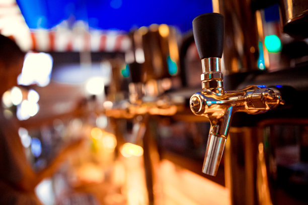 在餐厅或酒吧，调酒师在啤酒龙头处倾倒一杯生啤酒。照片具有复古柔和效果图片下载