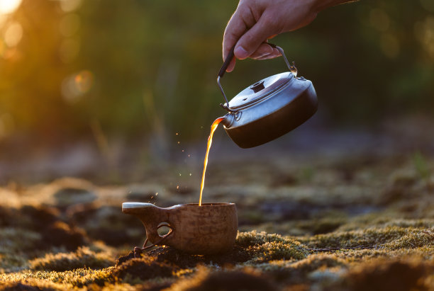 一名男子将咖啡从壶里倒进一个木库克萨马克杯里图片下载